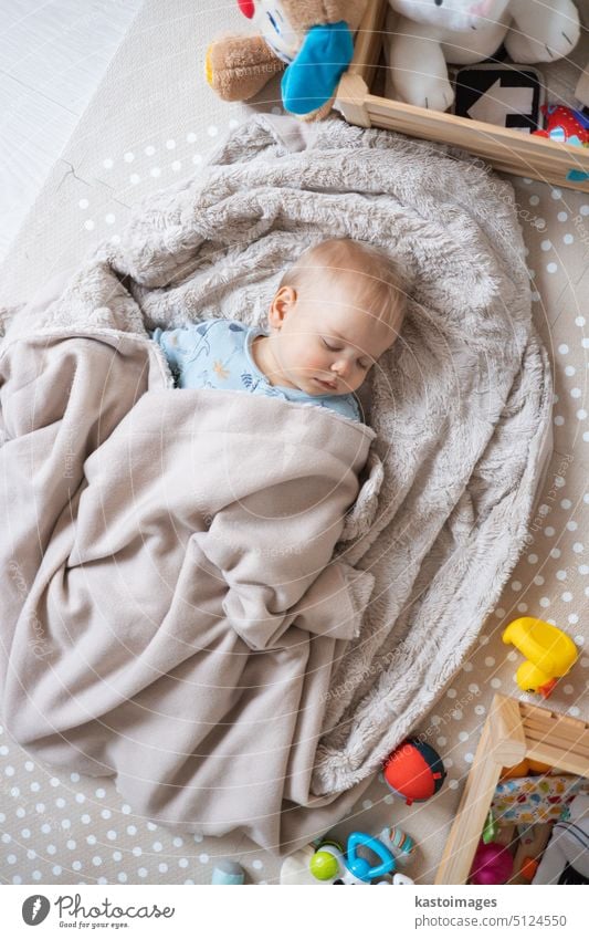 Cute infant baby boy sleeping on playing mat covered with warm cosy blanket caucasian childhood background little white innocence joy person small care innocent