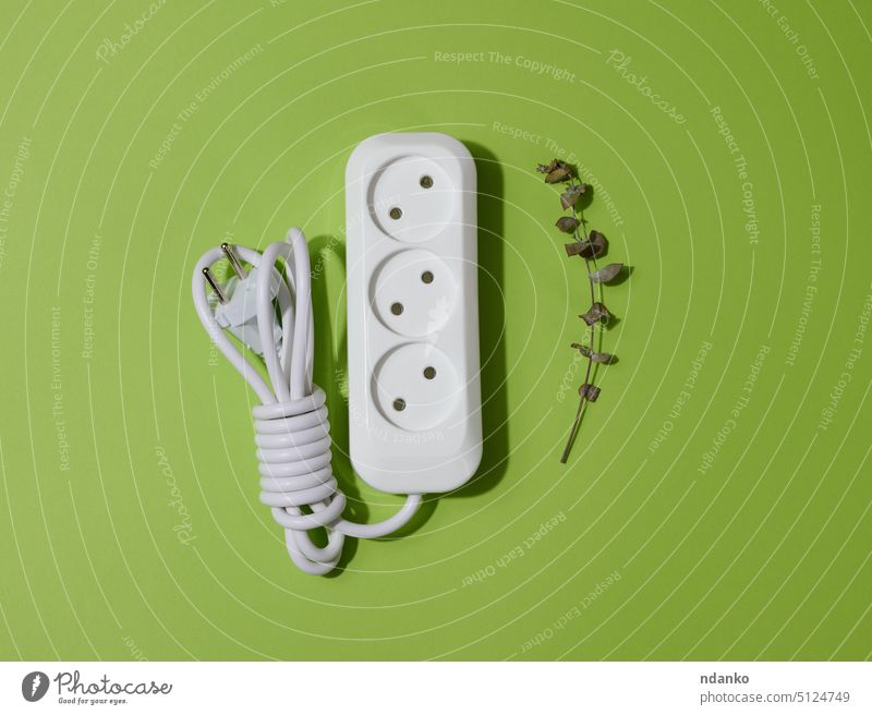 White plastic socket with cable on a green background, top view leaf eco power energy electricity technology plug voltage equipment electrical white connection