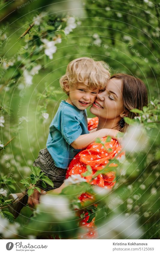 Beautiful touching scene of mom and toddler son in blooming spring garden. Happy mother and baby boy embracing. Family, love, childhood concept. family woman