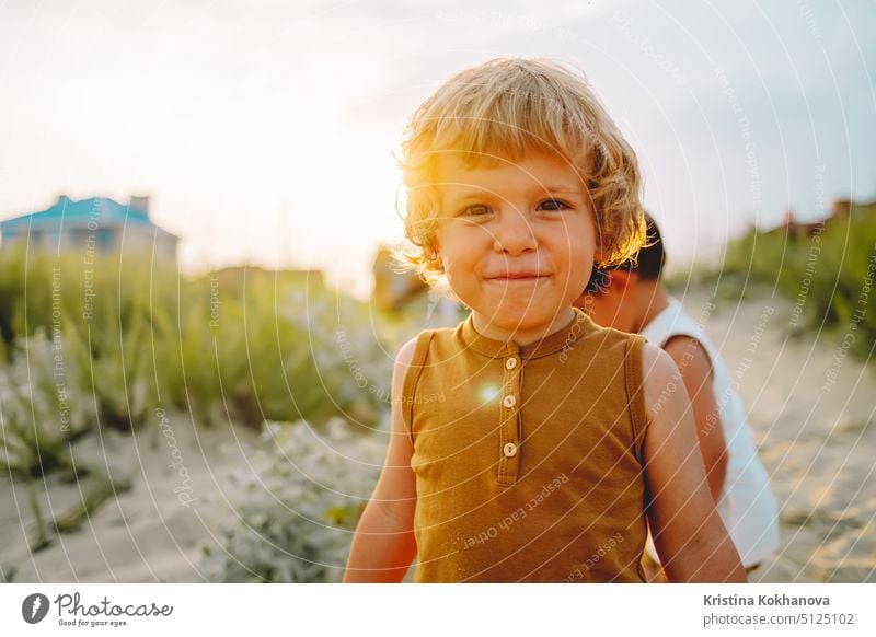 Portrait of cute little boy on natural background. summer sunny day. Toddler. Natural aestetic portrait of child. Golden hour. Smiling kid. sand beach fun