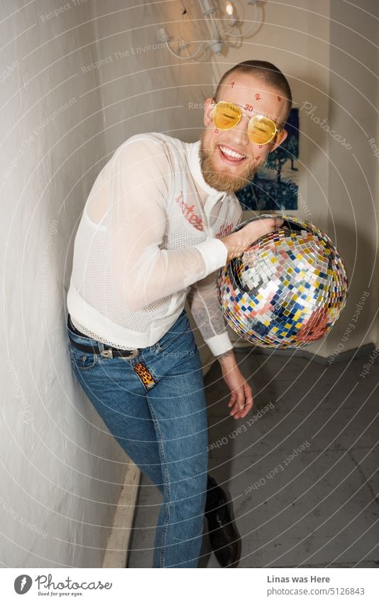 It’s time to turn on that festive mode! Like this wild man with a disco ball. Wearing yellow sunglasses and blue jeans. Showing his white teeth while smiling. Just being a party person all the way.