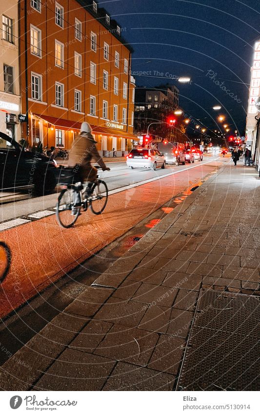 A cyclist riding through the city at night on the bike path next to cars Cycle path Dark Street Transport Vehicle Mobility Town Movement Traffic lights