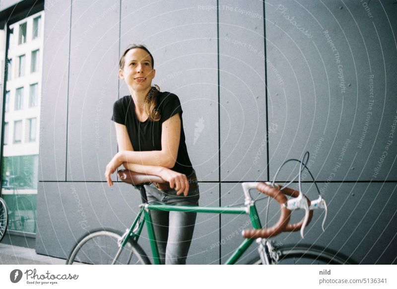 Young woman with green vintage racing bike in front of gray wall Racing cycle singlespeed urban Copy Space left Mobility Retro Lifestyle Bicycle