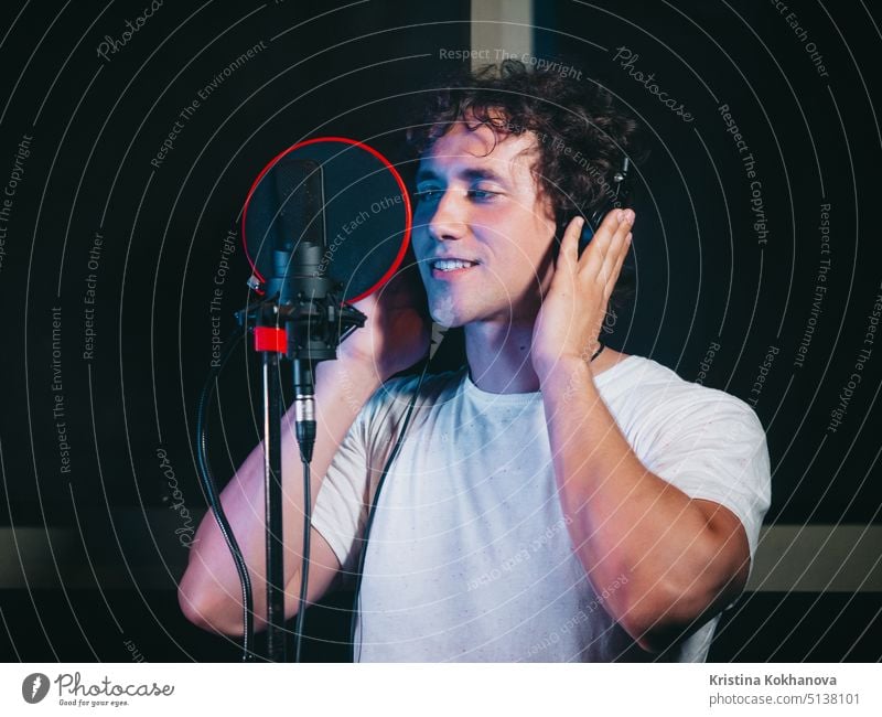 Male vocal artist with curly hair singing alone. Young handsome singer man emotionally writing song in the studio. Recording new melody or album. audio