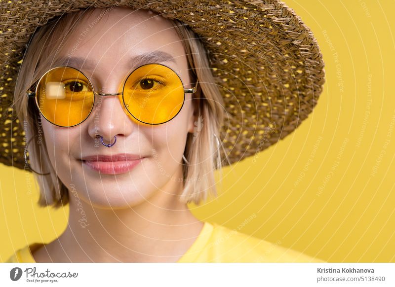 Portrait of young pretty blonde woman on summer yellow studio background. Confident sunny outfit with sunglasses and straw hat. adult beautiful female happy