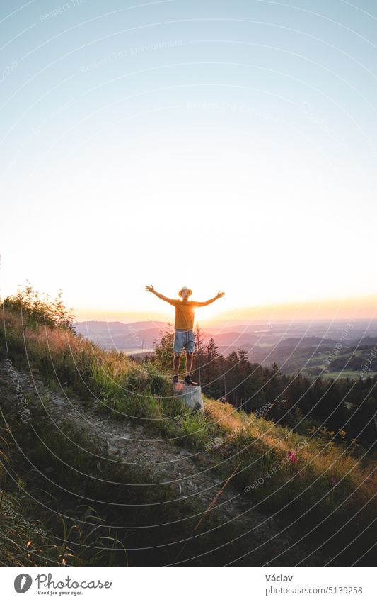 Joyful adventurer with a straw hat on his head enjoys the last touches of the sun on his journey through the countryside. Beskydy mountains, Czech republic