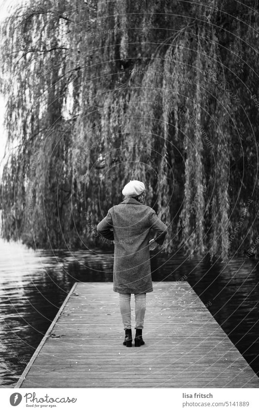 WOMAN - WATER - FOOTBRIDGE - WEEPING WILLOW Woman back view Hat Coat Chic Weeping willow Footbridge Water Black & white photo Loneliness by oneself Adults