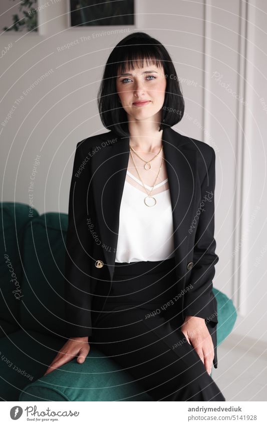 5141928 Beautiful Business Woman In Black Suit And White Blouse Is Sitting On The Green Sofa At Office Charming Brunette Female With Short Hair Is Looking In Camera Girl Is Working Indoors Photocase Stock Photo Large 
