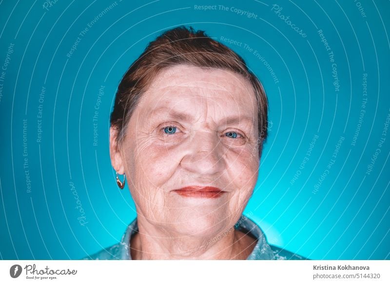 Caucasian kind grandmother looking at camera. Portrait of smiling aged woman in studio on blue background. elder elderly good human mature older pensioner real