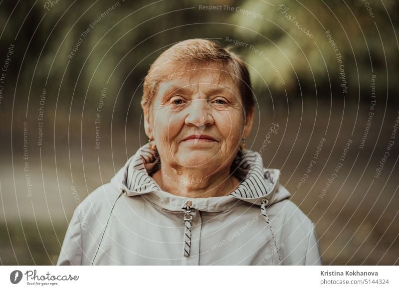 Beautiful portrait of smiling aged woman in autumn park. Caucasian grandmother looking at camera. elder elderly good human mature older pensioner real retired