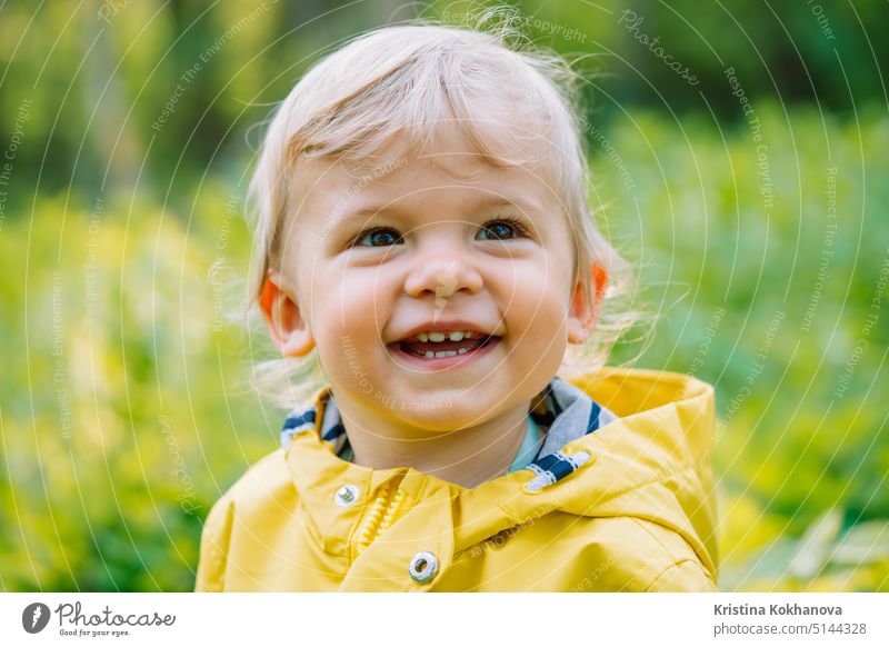 Portrait of cute baby boy in yellow raincoat. Child smiling. Love care attachment family children concept. a Royalty Free Stock Photo from Photocase