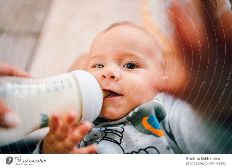 Little baby boy drinking mother milk from the bottle and smiling care caucasian child childhood cute food infant kid little adorable bed feeding girl happy