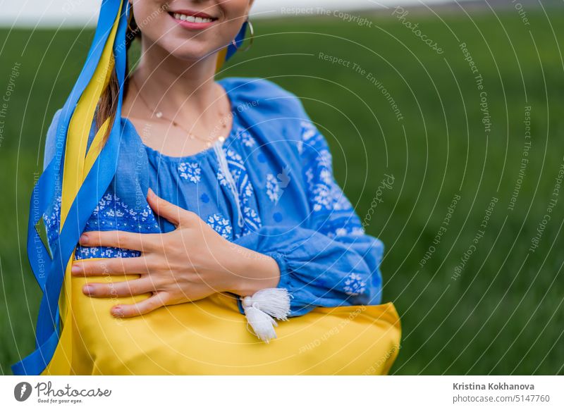 Smiling ukrainian woman with national flag on green field background. Young lady in blue embroidery vyshyvanka. Ukraine, independence, freedom, patriot symbol, victory in war.