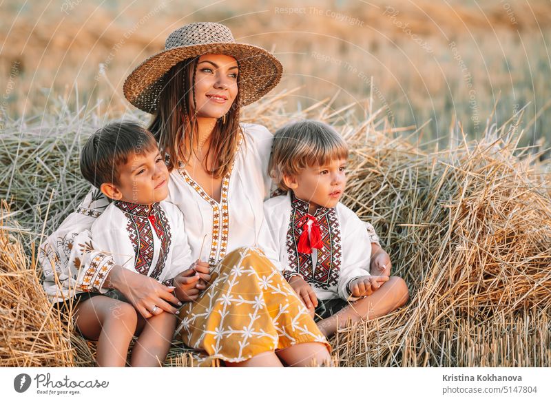 Ukrainian boys and mother sitting together on wheat in field after harvesting. Family, friends holding hands. Children is our future. Happy childhood. active
