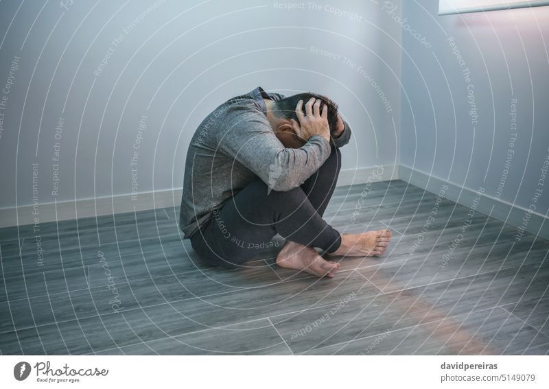 Unrecognizable man with problems sitting on the floor unrecognizable faceless desperate guy mental disorder holding head hands arms copy space anxiety sad