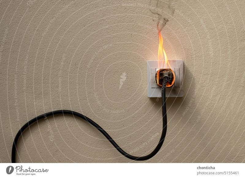 On fire electric wire plug Receptacle on the concrete wall exposed concrete background with copy space flame outlet receptacle socket rallonge shock power cable