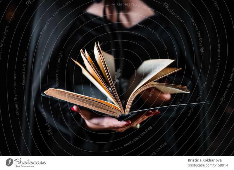 Witch in black costume reading black magic book. Halloween, spooky horror antique background bright concept conjure dark design dream education esoteric