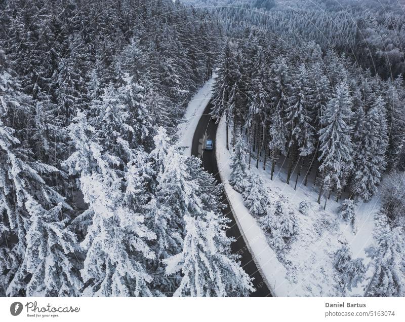 Snow-covered trees in the forest and asphalt road line in the mountains. Winter landscape in the mountains. Aerial drone panoramic photo. above aerial