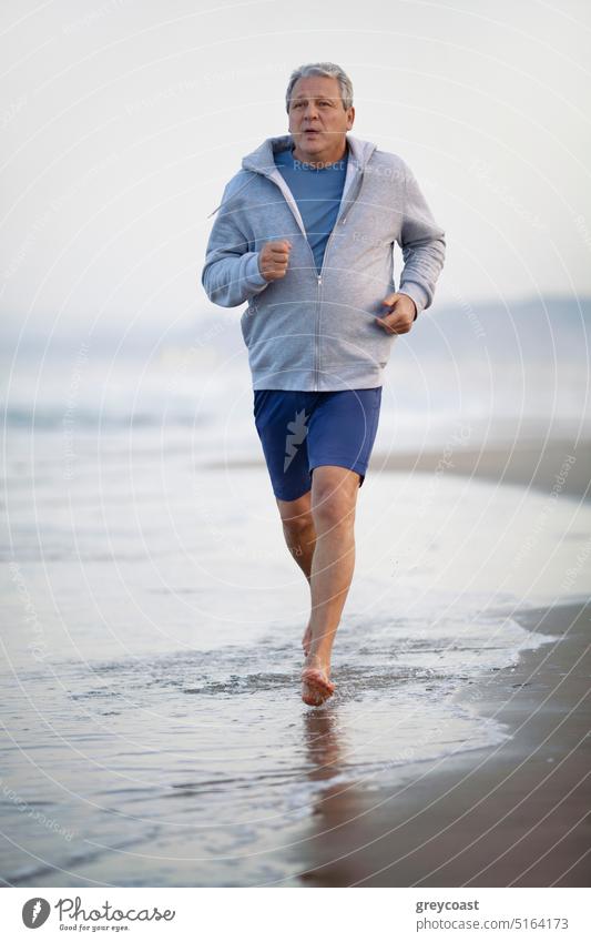 Active senior man jogging along the beach workout retired people sport run male retirement active training exercise runner older man healthy lifestyle sea