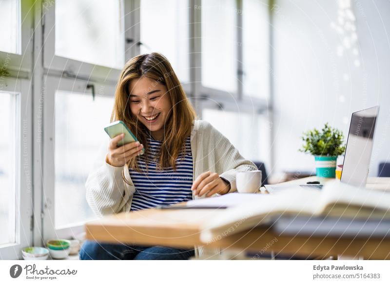 Young woman using smartphone in loft office real people millennials student indoors window natural girl adult attractive successful confident person beautiful