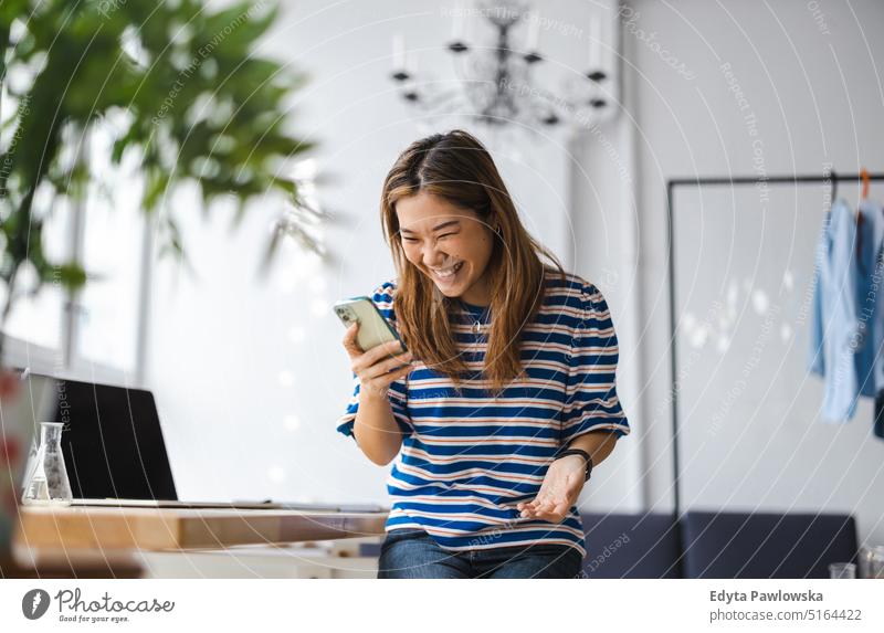 Young woman using smartphone in loft office real people millennials student indoors window natural girl adult attractive successful confident person beautiful