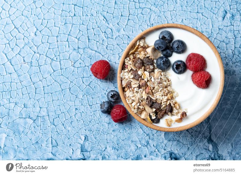 Yogurt with berries and muesli for breakfast in bowl on lbue background berry blue blueberry cereals closeup dairy delicious dessert diet food fresh fruit