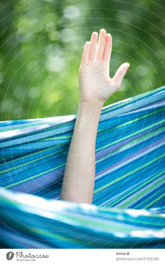 teenager's hand is stretched out of the hammock for low-contact greeting, hello teenie. The image is in portrait format with a lot of cool blue and green.