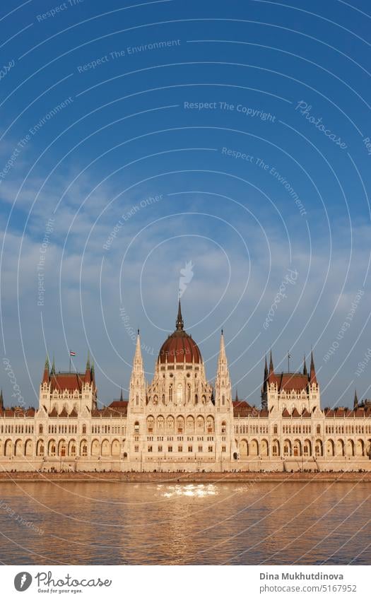 Hungarian Parliament Building in Budapest reflected in the water of Danube, photographed on sunny day with blue sky. Domed Neo-Gothic style architecture. Famous landmark for sightseeing in Hungary postcard view.