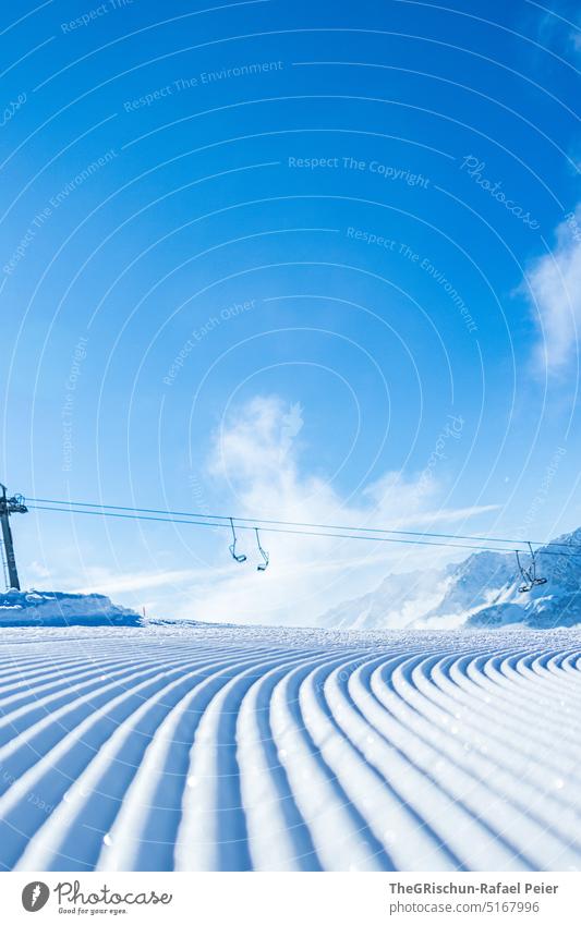 Fresh slope with chairlift in background against blue sky Snow Ski piste Cross-country ski trail chair lift Ski resort Blue sky Cold Pattern Winter