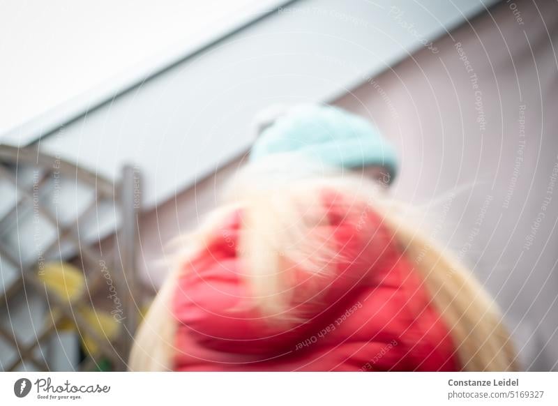 Child with red jacket and blowing hair. Girl Cap blurred hazy