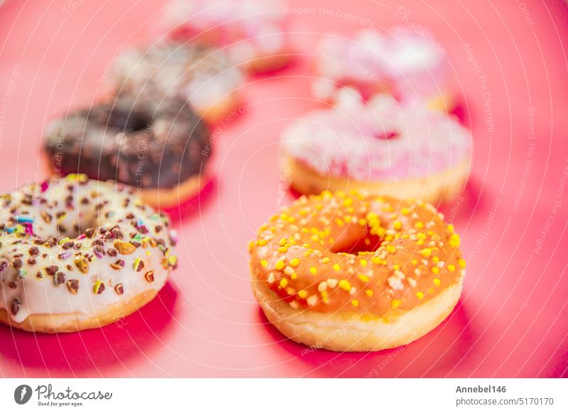 Doughnuts with multicolored glaze laid out in two rows on trendy pink background. Doughnuts are traditional sweet pastries. Copy space for text. food pastry