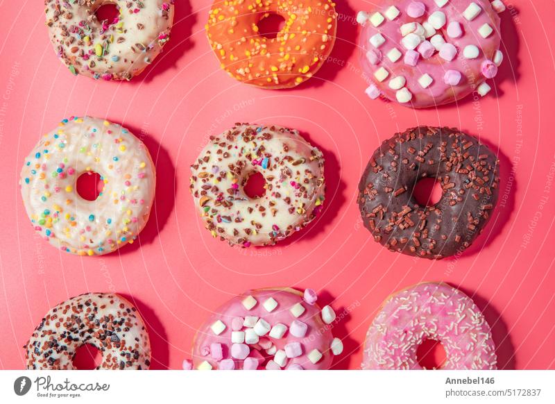 Donuts with icing on pastel pink background. Sweet donuts. top view assorted with various chocolate glazed and sprinkles, sugar sweets concept dessert doughnut