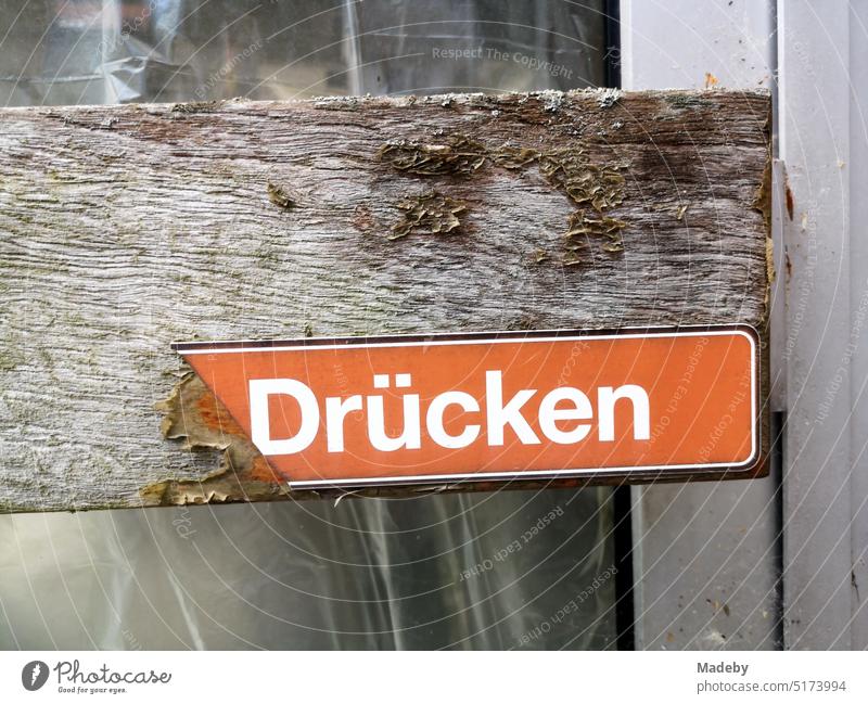 Improvised wooden handle with battered red sign pressing on the old entrance door of an empty store in Oerlinghausen near Bielefeld on the Hermannsweg in the Teutoburg Forest in East Westphalia-Lippe