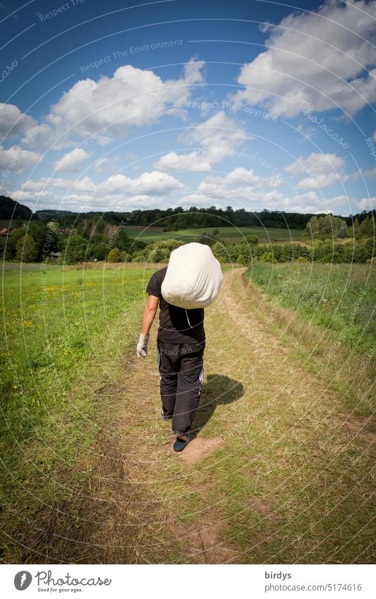 Back view of a man with luggage on his shoulder. Man walking along a dirt road off the beaten track tow duffel Carrying Nature go Rear view Luggage Going