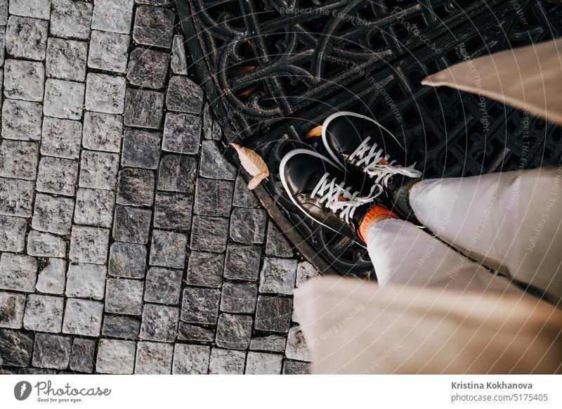 Female legs in sneakers on paving stones. Teenage feet top view. Prague street abstract adult background black block brick city construction detail fashion