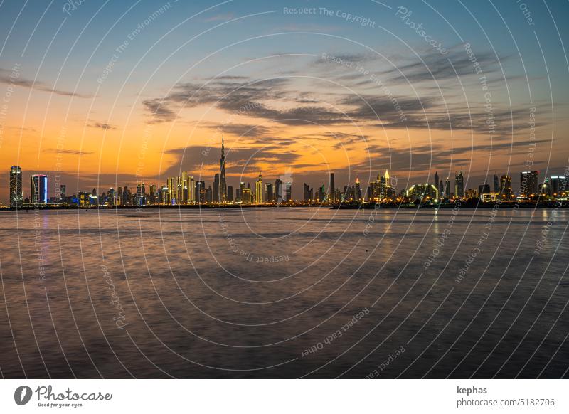 Dubai skyline with skyscrapers and creek at sunset, seen from Dubai Creek Harbour Burj Khalifa Downtown Dubai Skyline Water River Lake sea clouds evening