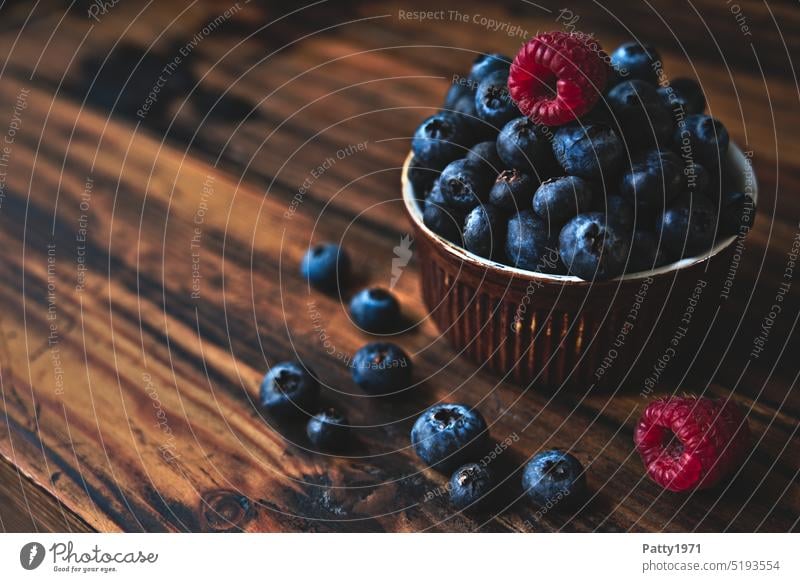 Blueberries and raspberries in a small bowl on a dark rustic wooden background Blueberry Raspberry Food photograph fruit Nutrition Delicious Vegetarian diet