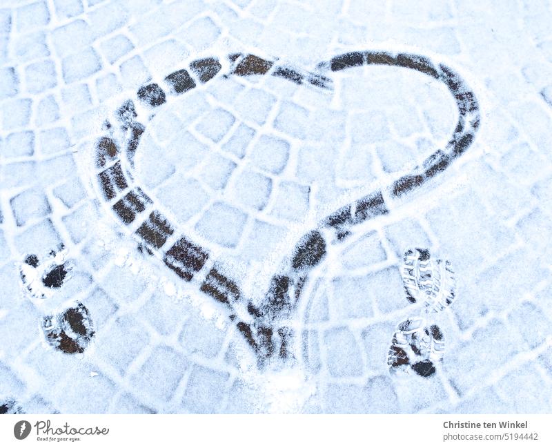 A painted heart and two shoe prints on lightly snowed cobblestones snowy cobbles Heart Winter Heart in snow Declaration of love Structures and shapes