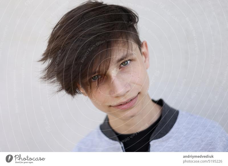 Handsome young man with stylish haircut. Portrait of teen boy with youth hairstyle is standing on grey background and looking at camera. face handsome lifestyle