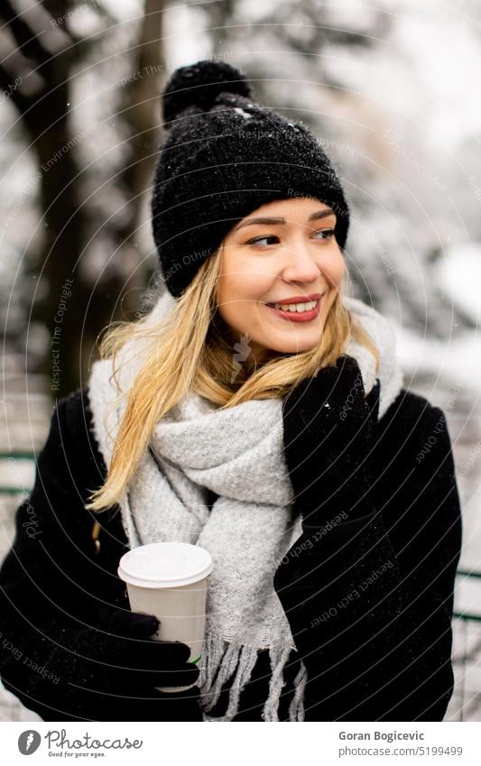 Young woman with Warm Clothes in Cold Winter Snow drinking coffee to go adult black clothing coat cold temperature glove hat one person portrait snow spring
