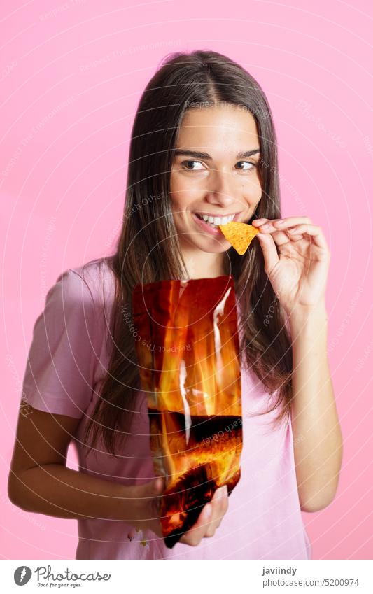Woman in pink t shirt eating chips woman smile positive nacho bite snack potato crisp junk food fast food unhealthy casual package tasty delicious crunch bright