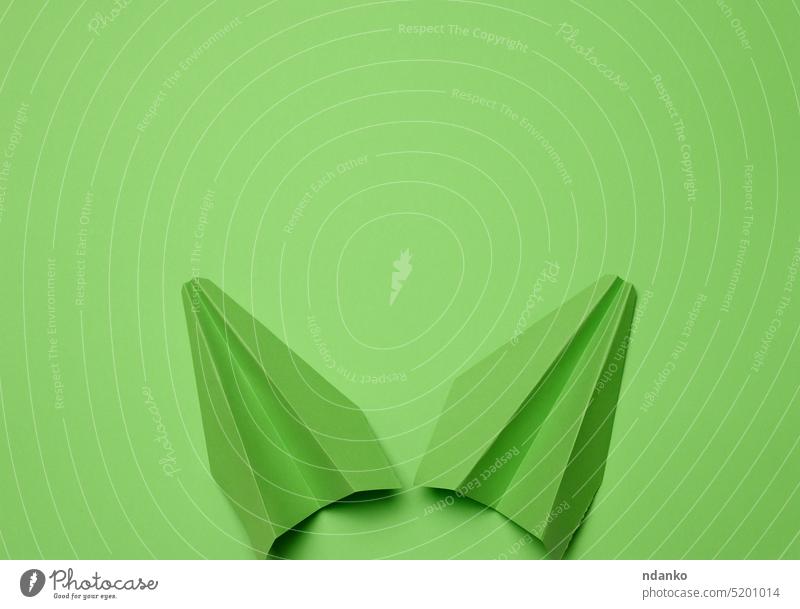 Green paper airplane on a green background, travel concept, top view. Copy space travelogue trip vacation wander wanderlust fly getaway itinerary journey