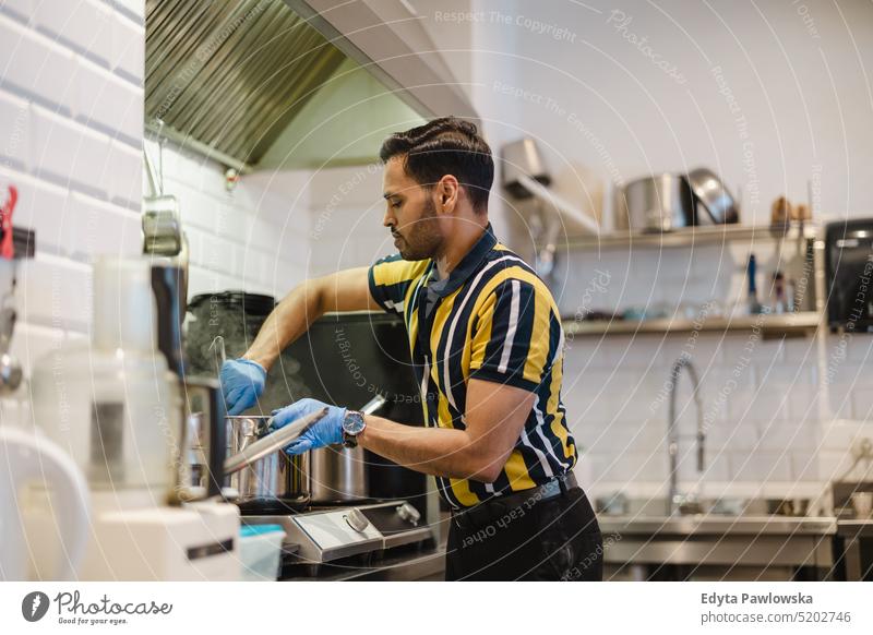 Young man preparing fresh food in commercial kitchen occupation owner young person employee professional job indian man asian catering making cooking vegan