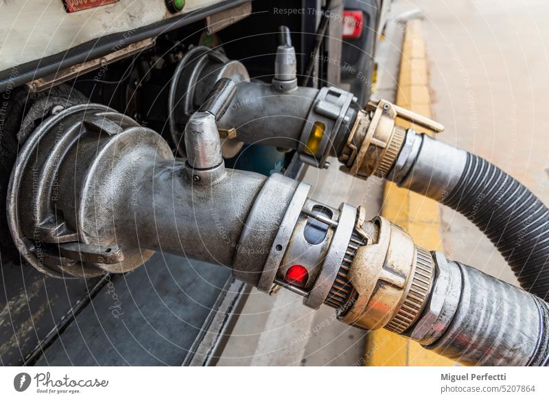 Devices attached to the mouths of a tanker truck to connect the discharge hoses, discharging subsidized diesel (diesel B or red) and normal diesel (diesel A) in the background.