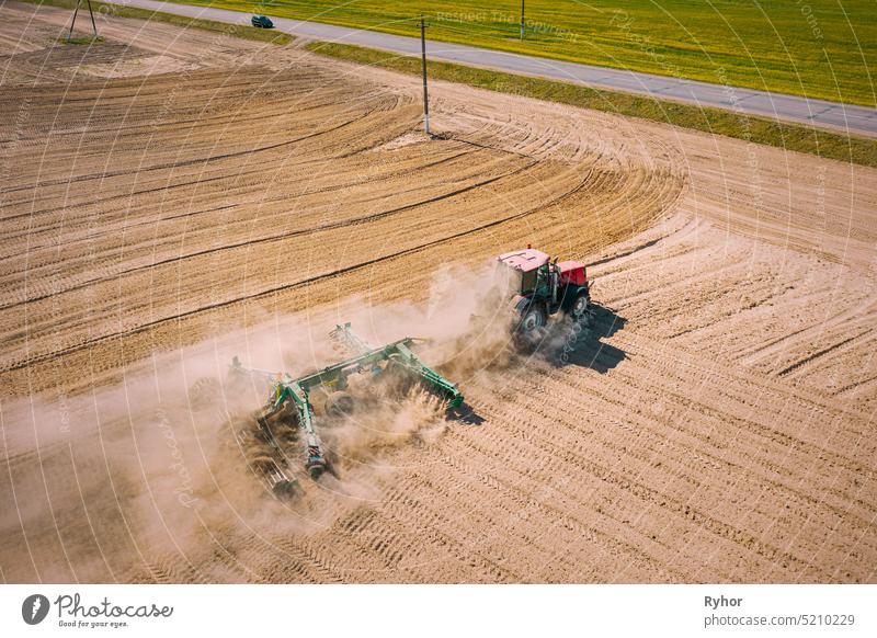 Aerial View. Tractor Plowing Field. Beginning Of Agricultural Spring Season. Cultivator Pulled By A Tractor In Countryside Rural Field Landscape. Dust Rises From Under Plows
