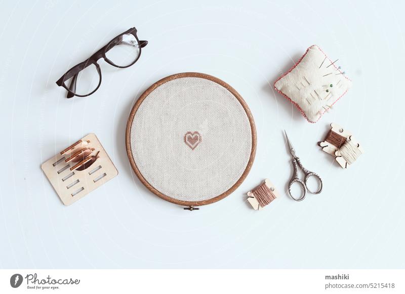 cross stitch embroidery accessories. Linen cloth in hoop on white background with floss, scissors and cloth. Indoor hobby concept. textile craft sewing thread
