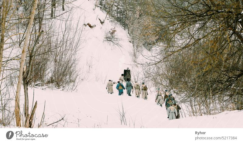 Men Dressed As White Guard Soldiers Of Imperial Russian Army In Russian Civil War Times Marching Through Snowy Winter Forest. Historical Reenactment 1917-1922.