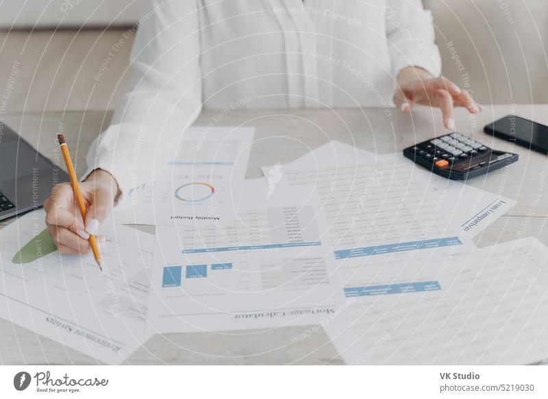 Female business person works calculating project budget, analyzing financial statistics, close-up female businessperson count calculate calculator desk graph