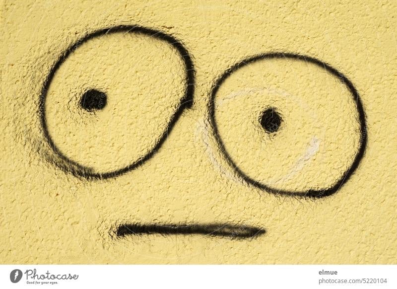 on a yellow wall with black drawn emoji with big eyes and neutral expression grimace Grimace Smiley Smiley drawing Neutral neutral view Draw Daub saucer eyes