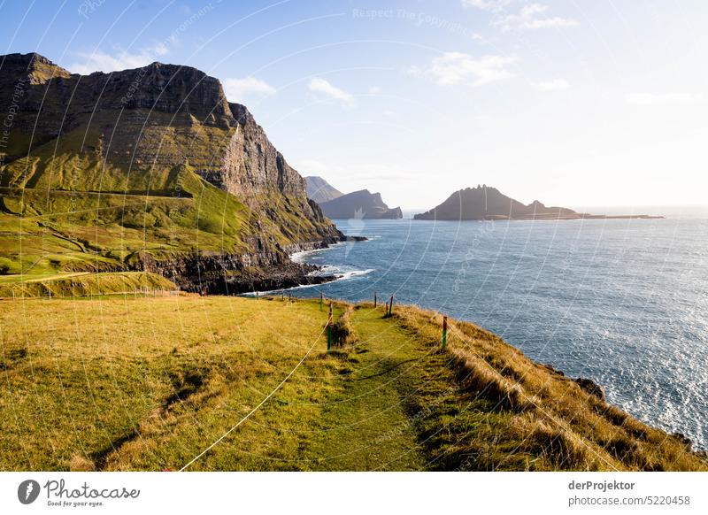 View of offshore island and path in sunlight Street rocky Bad weather Environment Hill Rock highlands Rural harmony Weather Picturesque Faroe Islands Sunlight